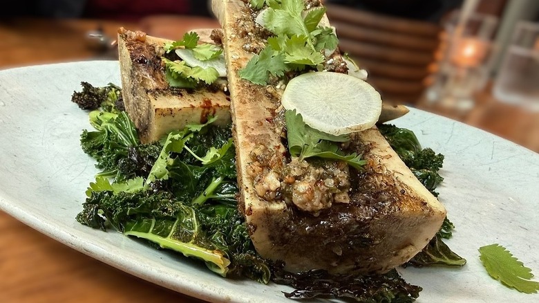 halved bones with roasted bone marrow on a bed of cooked kale, topped with fresh greens