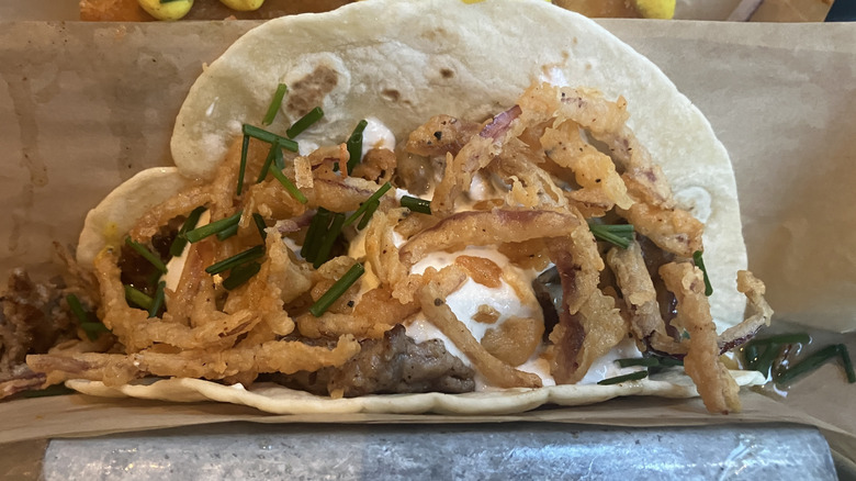 close up of taco full of beef and fried onions