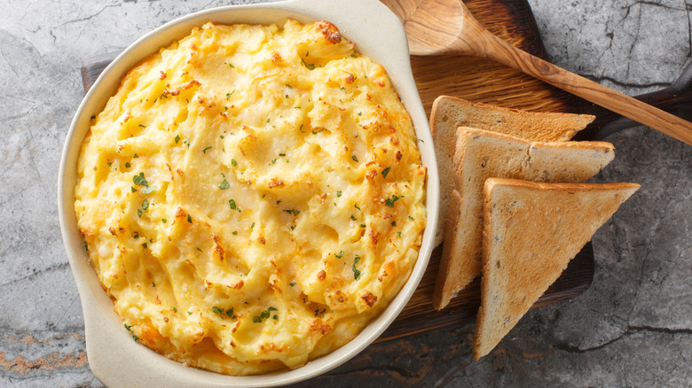 Mashed potatoes in a dish beside bread and a spoon