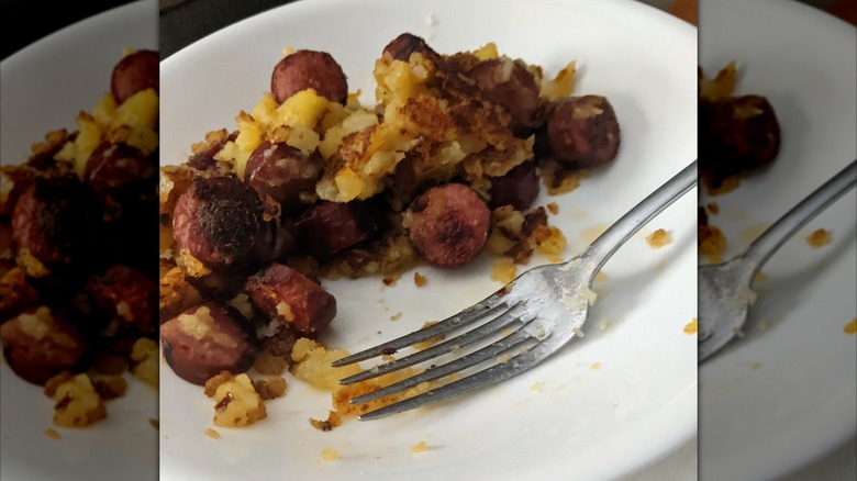Fork with hot dogs and fried potatoes