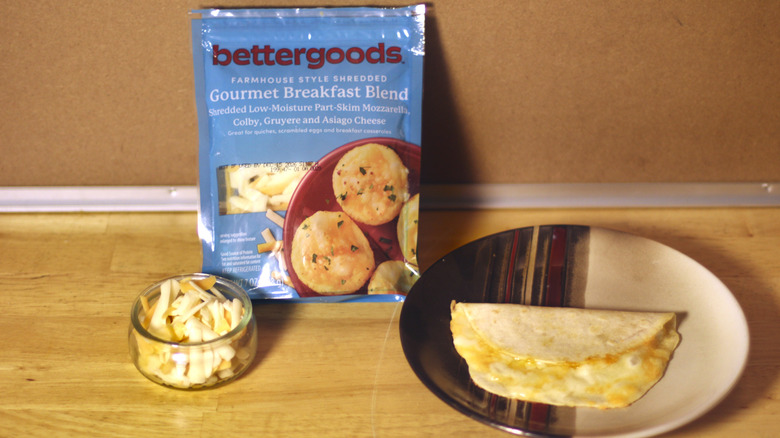 A bag of Bettergoods Gourmet Breakfast Blend beside a dish of the unbagged cheese and a small quesadilla on a plate