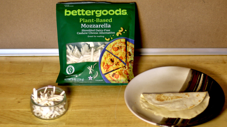 A bag of Bettergoods Plant-Based Mozzarella cashew cheese beside a dish of the unbagged cheese and a small quesadilla on a plate