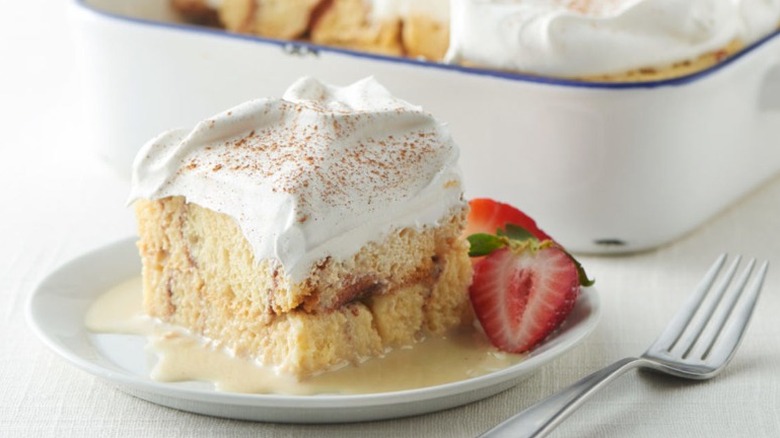 a slice of tres leches cake made with cinnamon rolls with whipped topping and slice strawberries