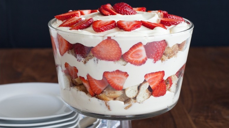 a trifle in a glass dish with layers of pudding, cinnamon roll pieces, and strawberries
