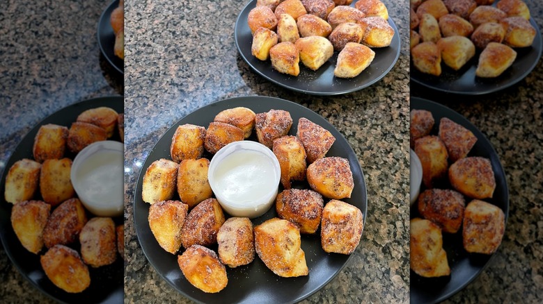 two plates of cinnamon roll bites covered in cinnamon sugar with a cup of icing in the center for dipping