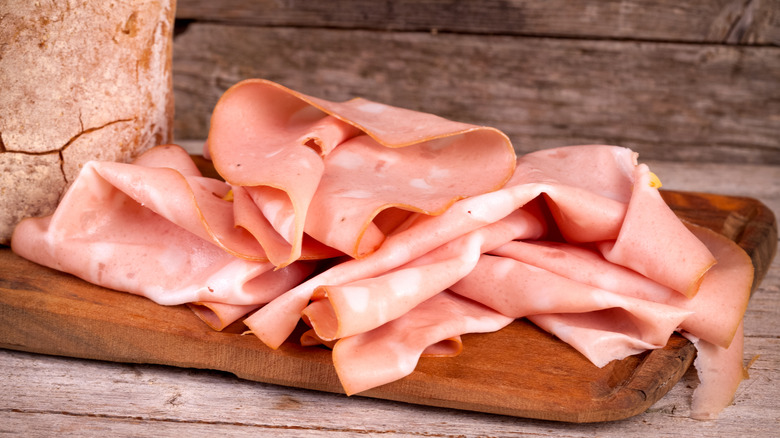 slices of Italian mortadella on wooden cutting board