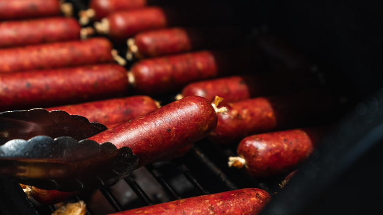 close-up of sausage being turned in smoker