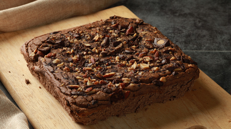 large brownie loaf with nuts on top of cutting board