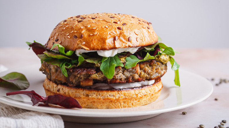 lentil burger on seeded bun on white plate