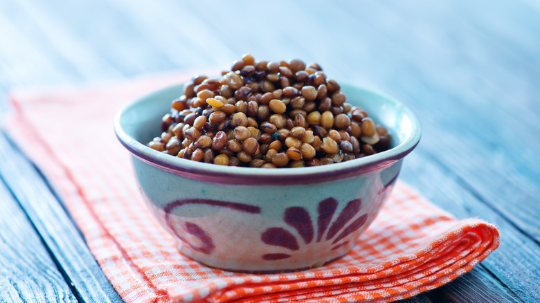 Bowl of cooked lentils on red and white towel