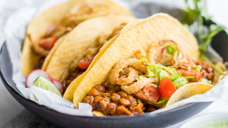 lentil tacos on yellow corn shells in black bowl