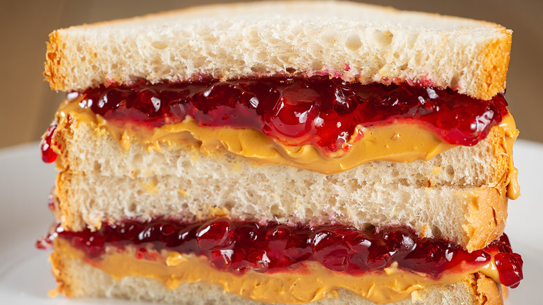 close up of peanut butter and red jelly sandwich halves stacked on top of one another