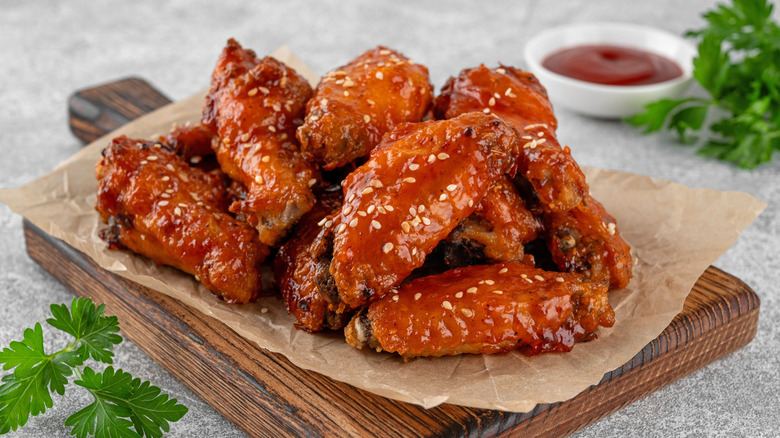 Pile of hot glazed chicken wings with sesame seeds on board