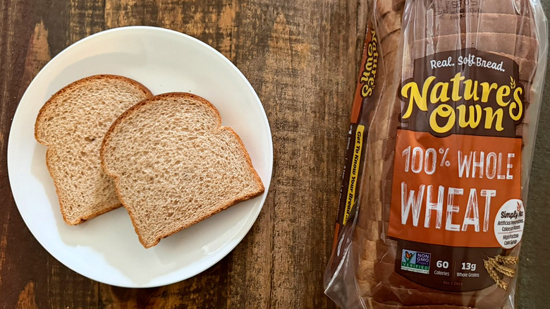 Two slices of Nature's Own 100% Whole Wheat bread next to a loaf of the same bread