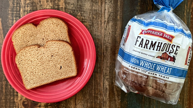 Two slices of Pepperidge Farm Farmhouse 100% Whole Wheat bread next to a loaf of the same bread