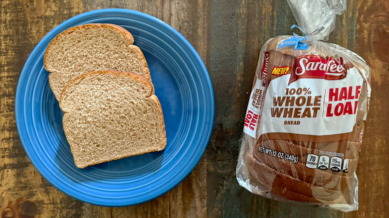 Two slices of Sara Lee 100% Whole Wheat bread next to a loaf of the same bread