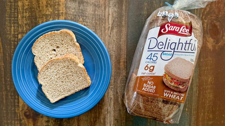 Two slices of Sara Lee Delightful Soft & Smooth Wheat bread next to a loaf of the same bread