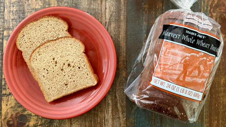 Two slices of Trader Joe's Harvest Whole Wheat bread next to a loaf of the same bread
