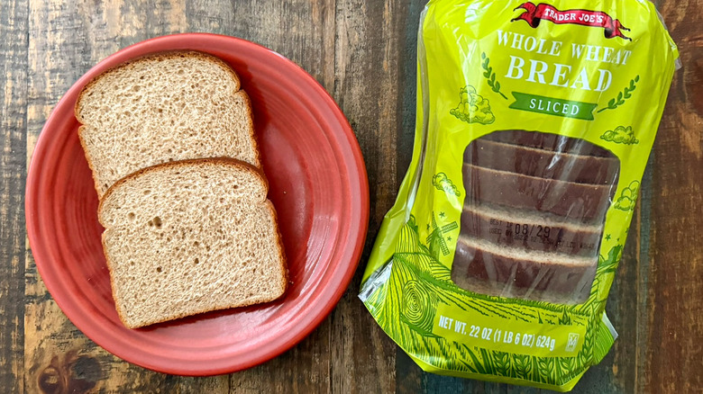 Two slices of Trader Joe's Whole Wheat Sliced bread next to a loaf of the same bread