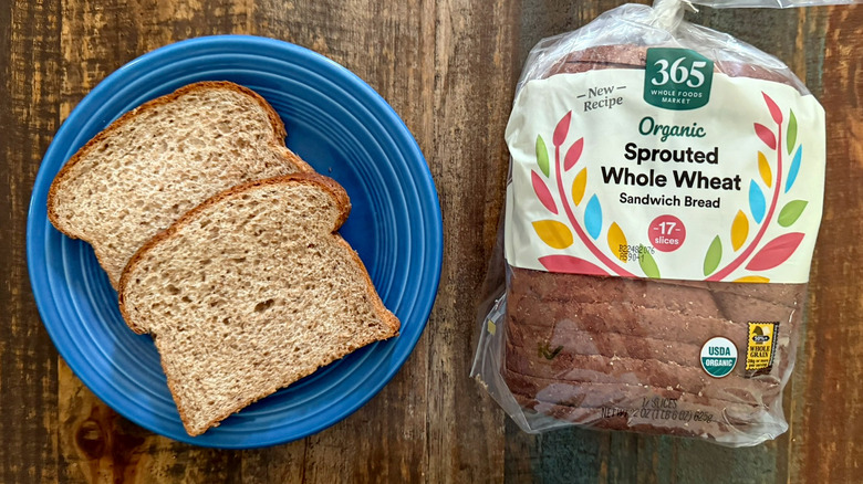Two slices of Whole Foods Market 365 Organic Sprouted Whole Wheat Sandwich bread next to a loaf of the same bread