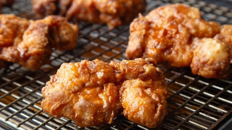 Pieces of crispy fried chicken with hot honey mustard glaze on cooling rack