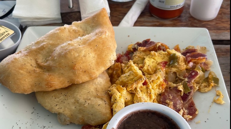 A plate of scrambled eggs with fry jacks and bean stew