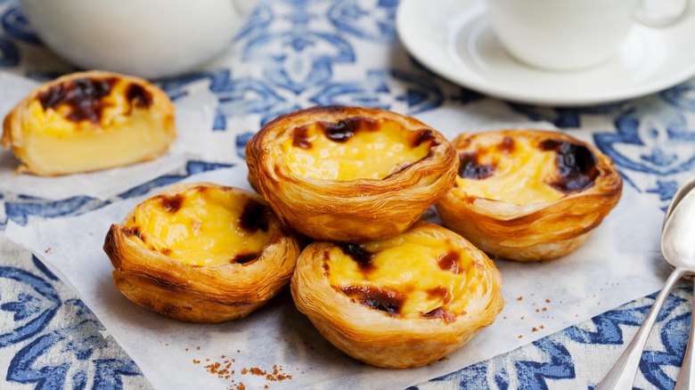 Portuguese pastel de nata custard tarts piled up on a blue and white table