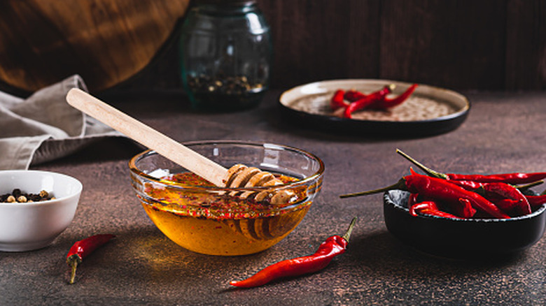 Hot honey in a bowl with chili peppers on the side