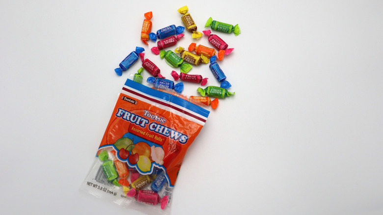 open bag of Tootsie Fruit Chews spilling out onto a white surface