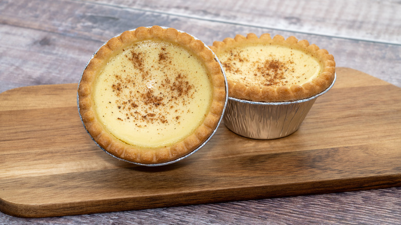 Two English egg custard tarts on wooden board