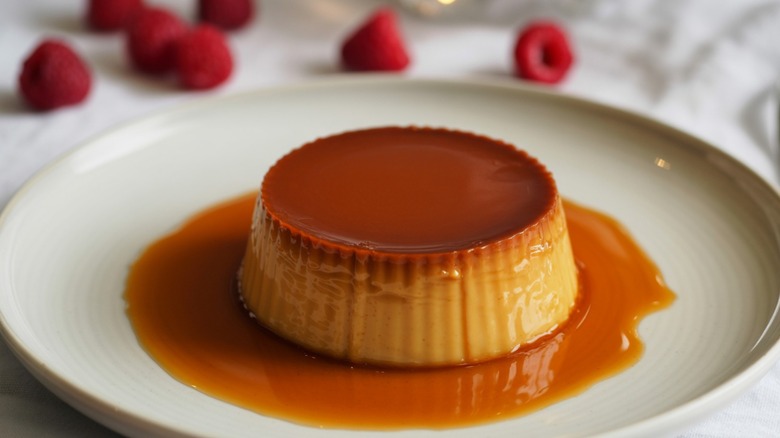 traditional flan dessert on a plate with raspberries in the background
