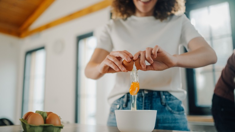 Woman baker cracking an egg into a bowl