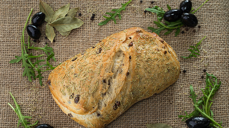 loaf of olive bread with olives on a piece of burlap