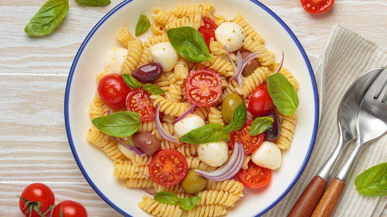 Mediterranean-style pasta salad with mozzarella, basil, cherry tomatoes, olives, and red onions