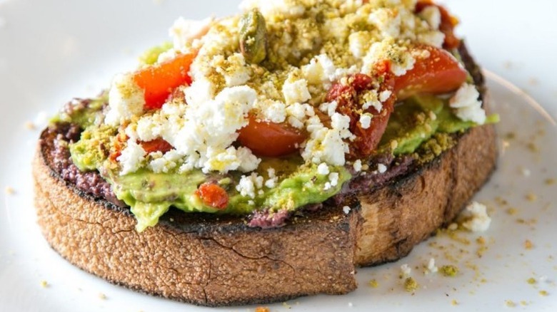 avocado toast with tapenade, tomatoes, and feta
