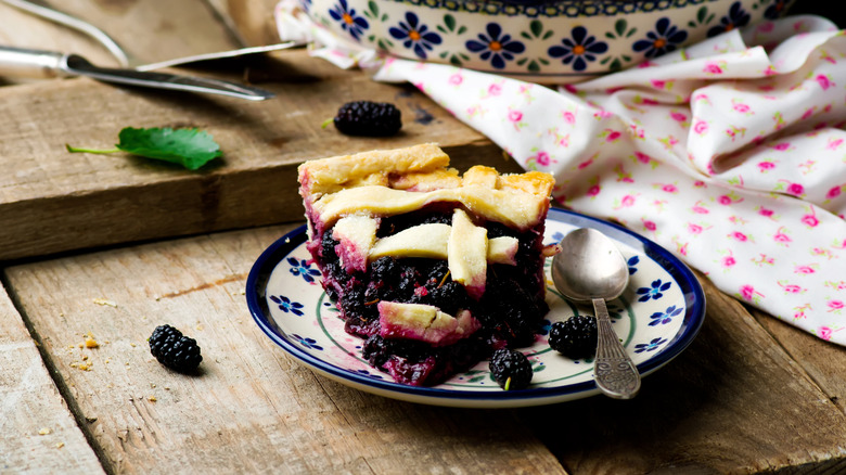 Slice of mulberry pie on a decorative plate on rustic wooden table