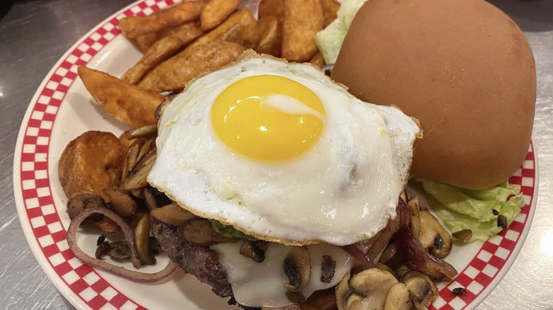 Sunny side up egg on burger with fries