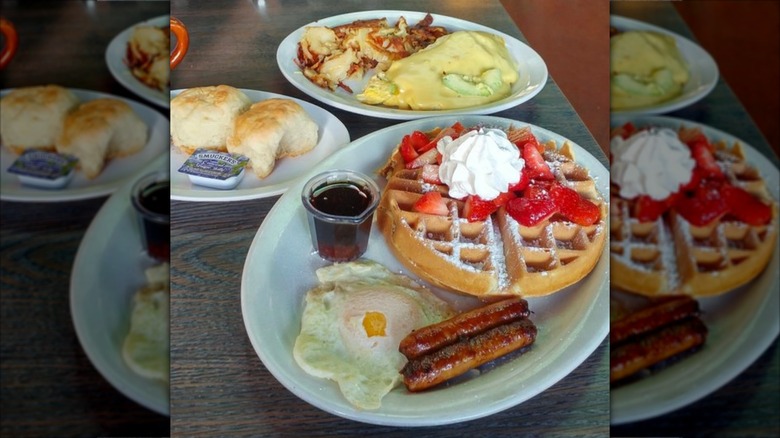 Plates with breakfast foods such as waffles, sausages, and biscuits