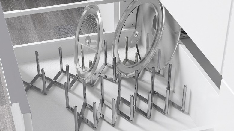 Variera pot lid organizer holding two clear pot lids sitting in a white kitchen drawer