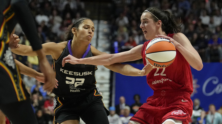 Caitlin Clark guarding basketball from opposing player