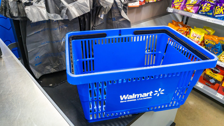 A Walmart shopping basket sitting in front of checkout aisle snacks.