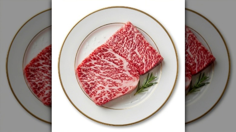 Raw wagyu steak on a white plate with a gold rim