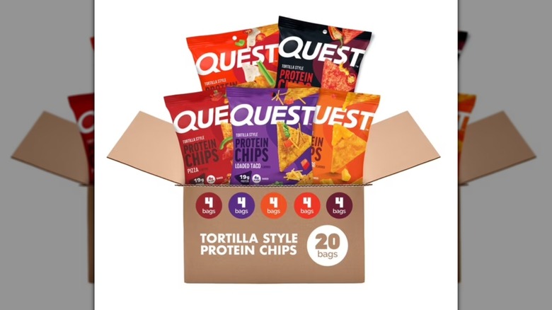 Cardboard box holding variety of flavors of Quest Tortilla Style Protein Chips on a white background.