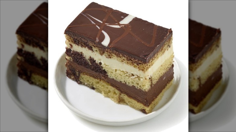 Private Selection Tuxedo Mousse Layer Cake Slice with Dark Chocolate Ganache on a white plate on a white background.