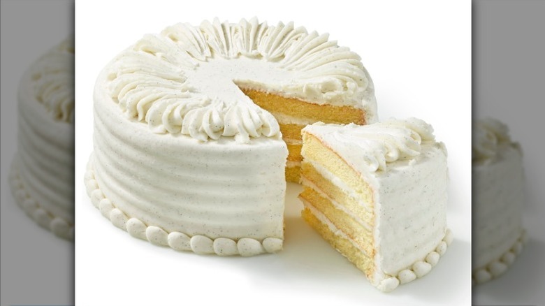 Private Selection Vanilla Bean Iced Four Layer White Cake with one slice separated on a white background.