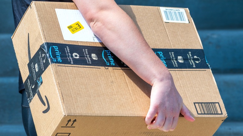An Amazon delivery worker carrying a cardboard box
