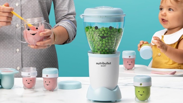 NutriBullet Baby baby food maker pictured with a small child and an adult who are each holding one of the cups that come with the kit
