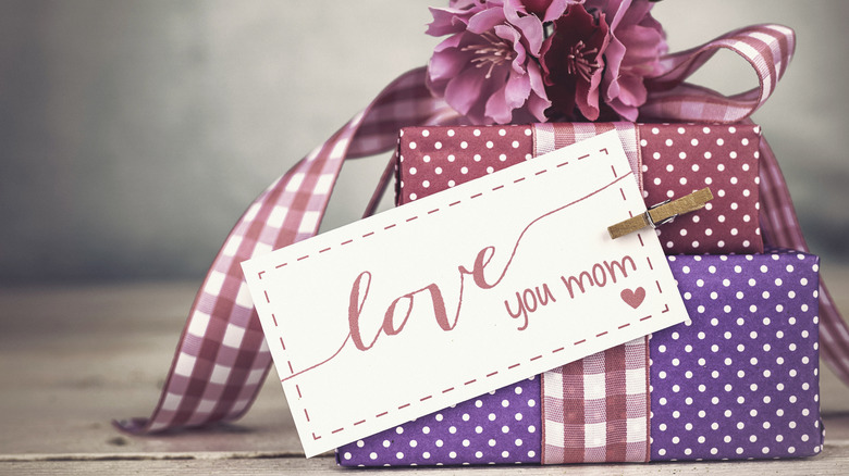 Mother's Day gifts in purple wrapping paper with flowers, a ribbon, and a card