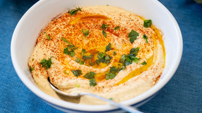 a bowl of hummus sprinkled with paprika and fresh herbs