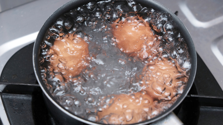 brown eggs boiling in a pot of water